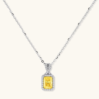 Platinum-plated 925 sterling silver necklace with a yellow radiant-cut moissanite pendant in a sparkling halo on a cream background.