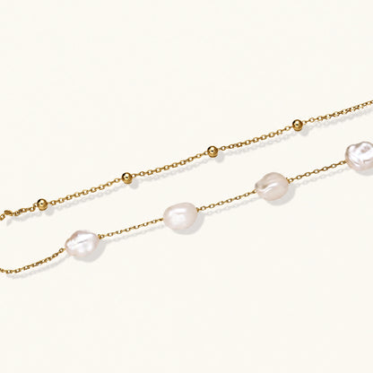 Double-strand gold bracelet with irregular baroque pearls and smooth freshwater pearls on cream background.