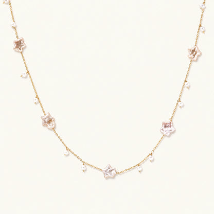 Gold vermeil chain with iridescent star-shaped baroque pearls and small round freshwater pearl drops on cream background.