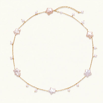 Gold vermeil chain with iridescent star-shaped baroque pearls and small round freshwater pearl drops on cream background.