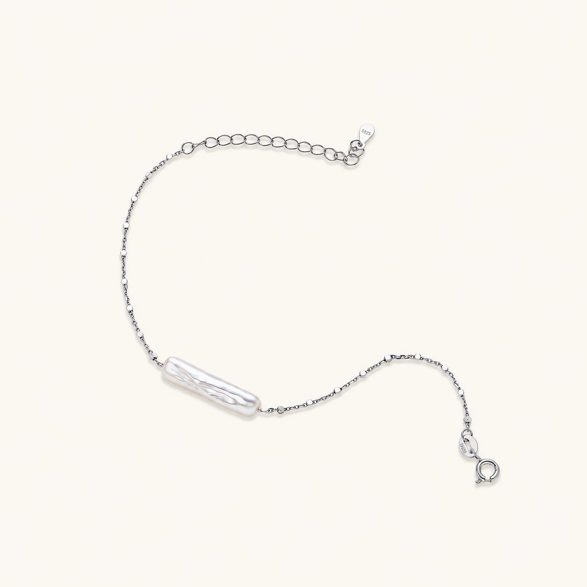 Minimalist bracelet with iridescent baroque pearl on rhodium-plated sterling silver chain against cream background