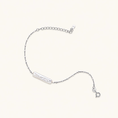 Minimalist bracelet with iridescent baroque pearl on rhodium-plated sterling silver chain against cream background