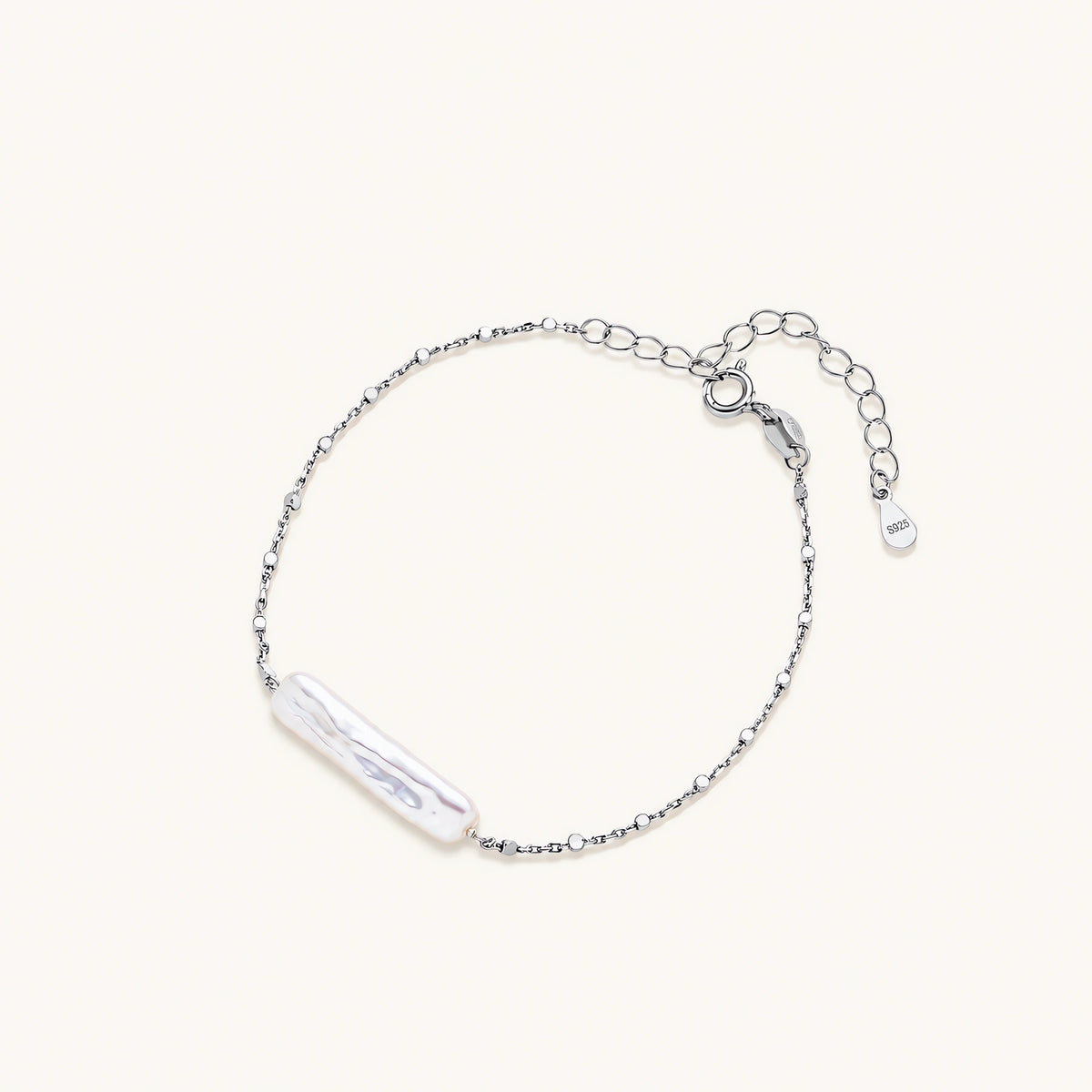Minimalist bracelet with iridescent baroque pearl on rhodium-plated sterling silver chain against cream background