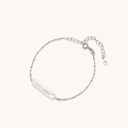 Minimalist bracelet with iridescent baroque pearl on rhodium-plated sterling silver chain against cream background