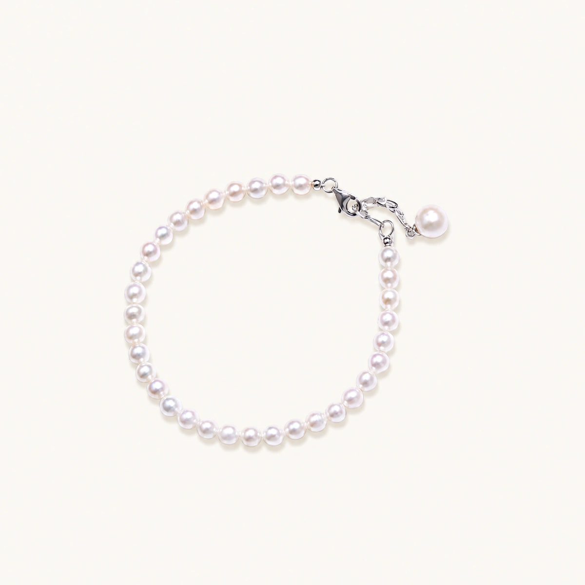 adjustable bracelet featuring lustrous freshwater pearls with rhodium-plated sterling silver clasp on cream background.