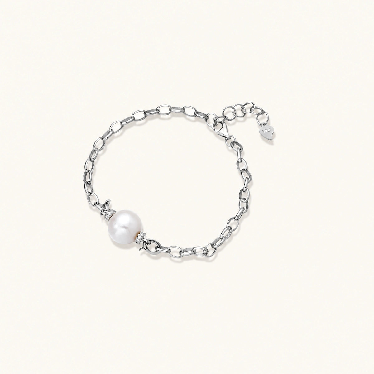 rhodium-plated silver chain bracelet with single white freshwater pearl and heart charm clasp on cream background