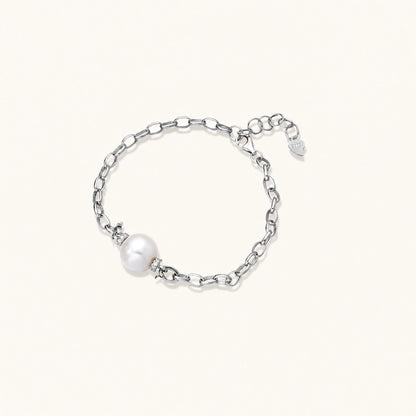 Rhodium-plated silver chain bracelet with single white freshwater pearl and heart charm clasp on cream background