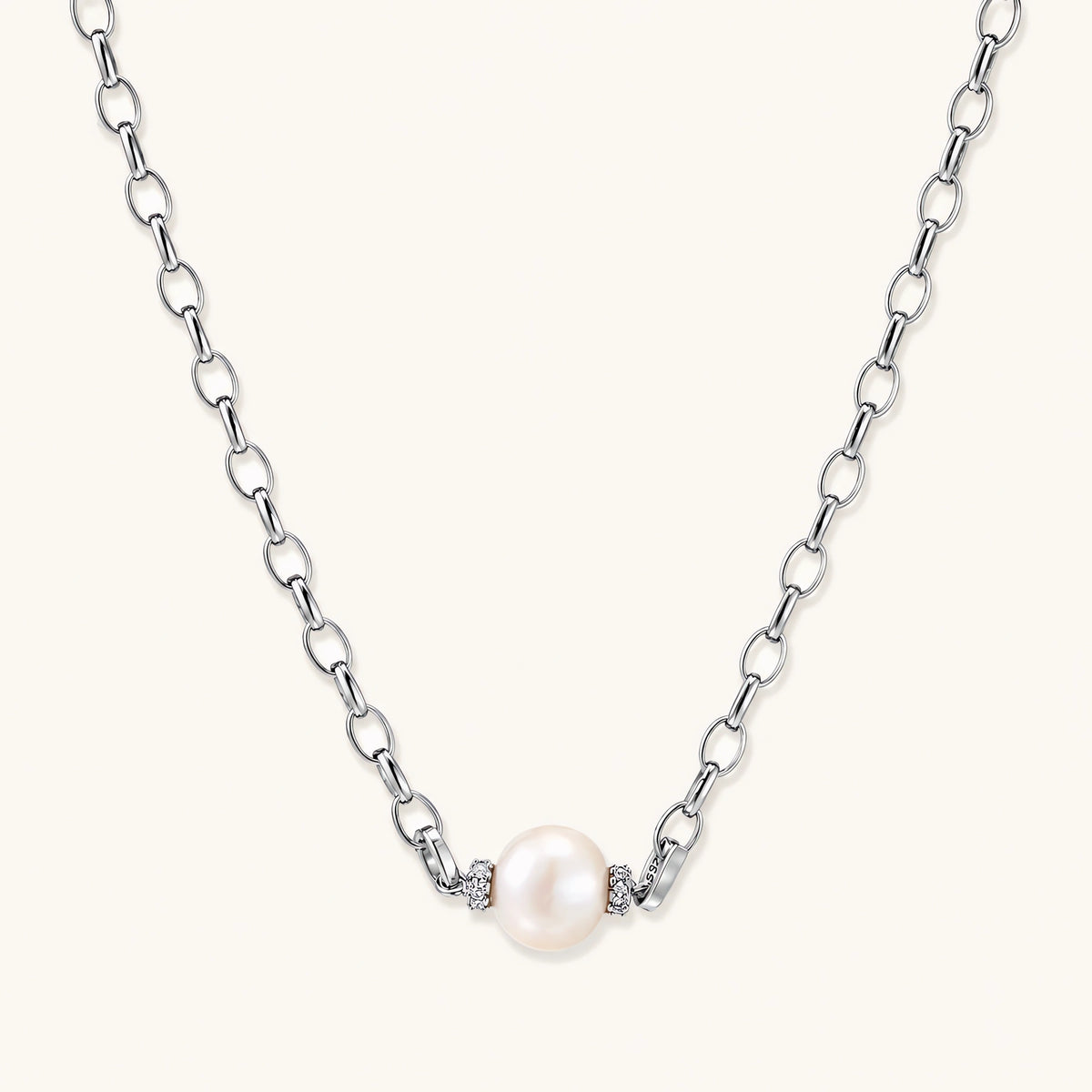 dainty rhodium-plated silver chain necklace with centered 10mm freshwater pearl and crystal accents on cream background