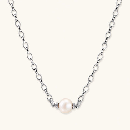 Dainty rhodium-plated silver chain necklace with centered 10mm freshwater pearl and crystal accents on cream background