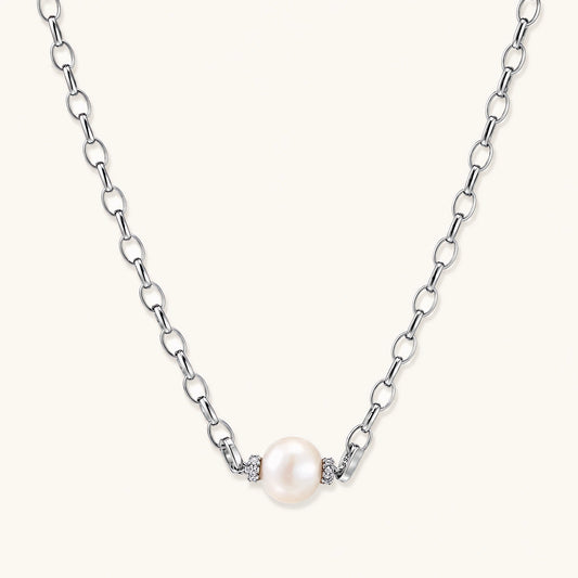 Dainty rhodium-plated silver chain necklace with centered 10mm freshwater pearl and crystal accents on cream background