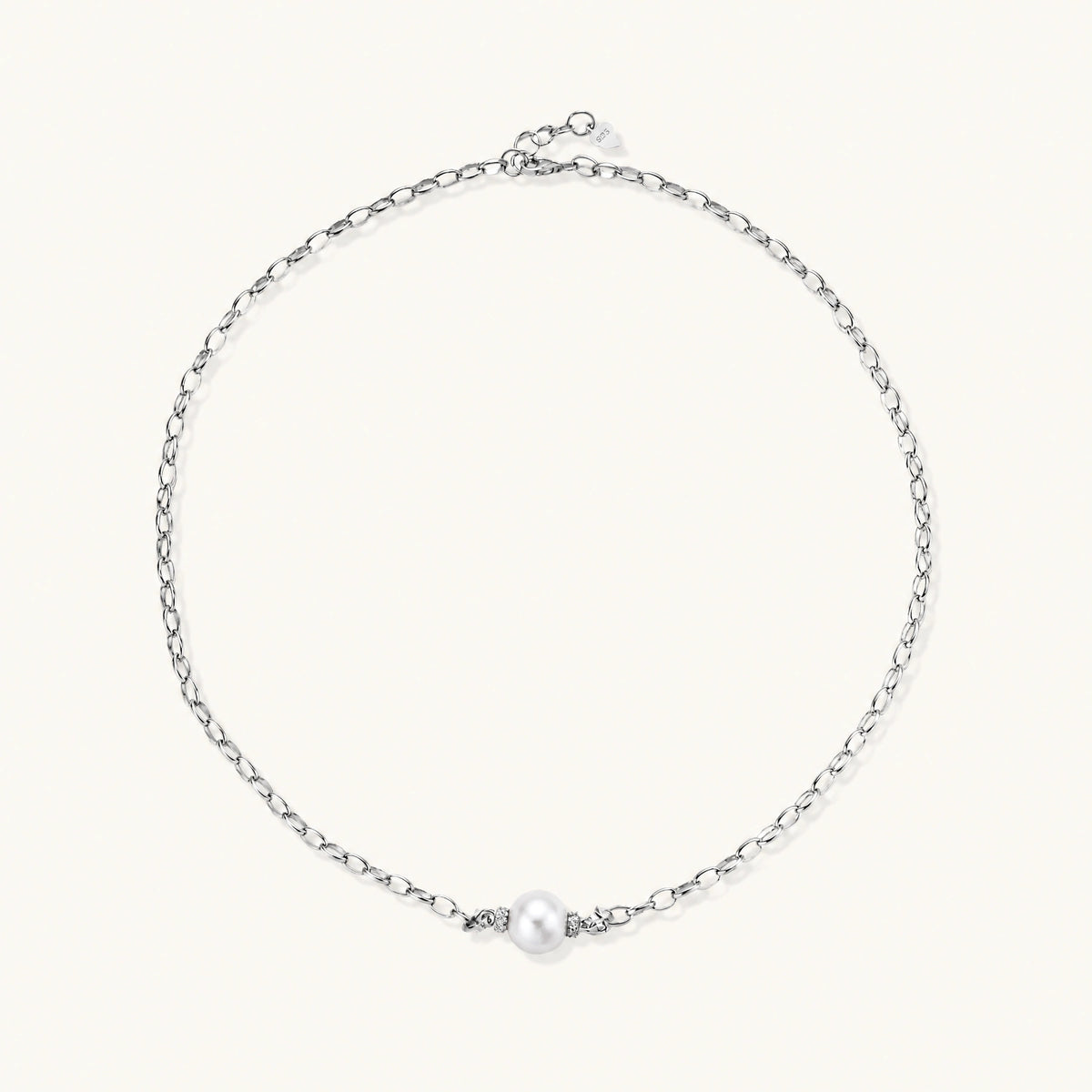 Dainty rhodium-plated silver chain necklace with centered 10mm freshwater pearl and crystal accents on cream background