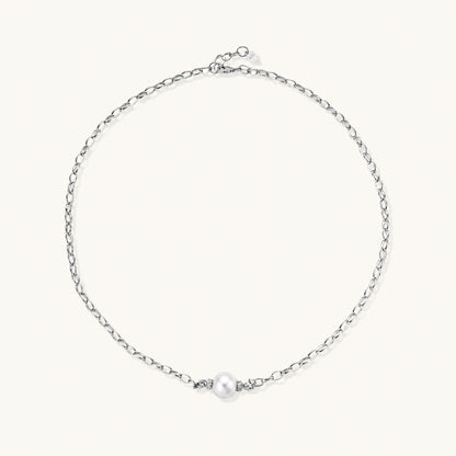Dainty rhodium-plated silver chain necklace with centered 10mm freshwater pearl and crystal accents on cream background