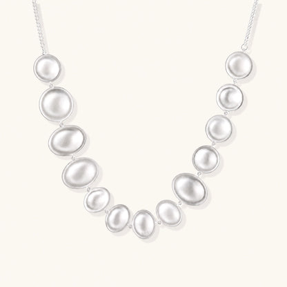Sterling silver necklace with fourteen matte concave round and oval discs on a curb chain with an adjustable extender.