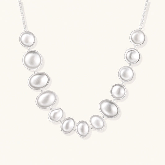 Sterling silver necklace with fourteen matte concave round and oval discs on a curb chain with an adjustable extender.