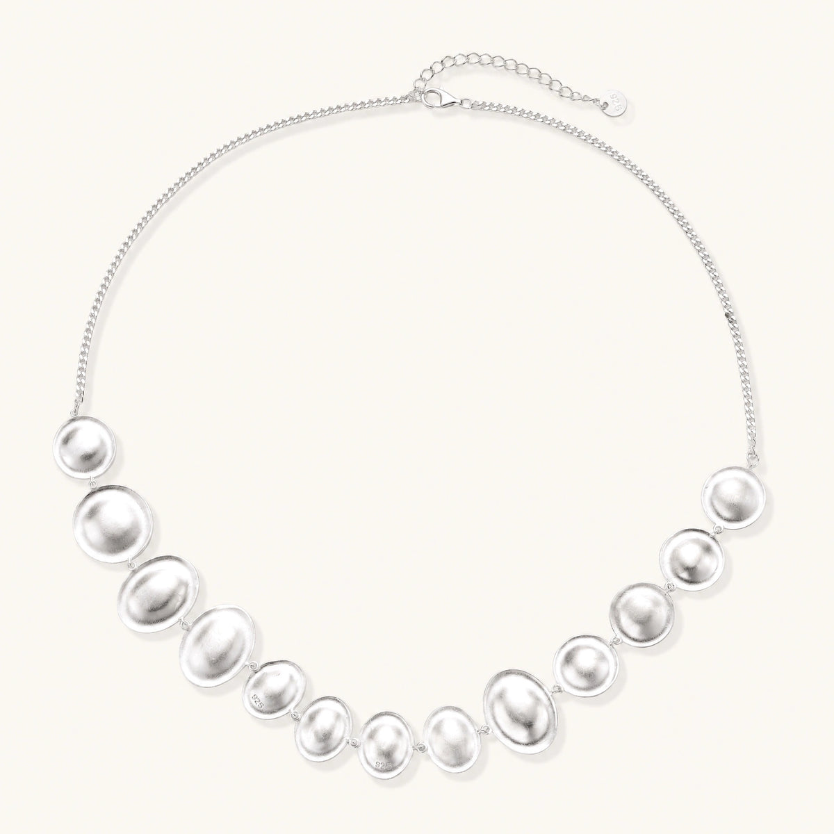 Sterling silver necklace with fourteen matte concave round and oval discs on a curb chain with an adjustable extender.