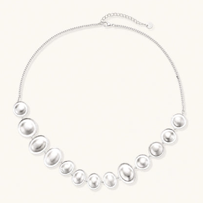 Sterling silver necklace with fourteen matte concave round and oval discs on a curb chain with an adjustable extender.