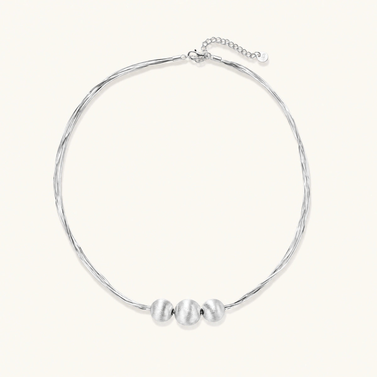 sterling silver multi-strand necklace with three brushed round beads on cream background