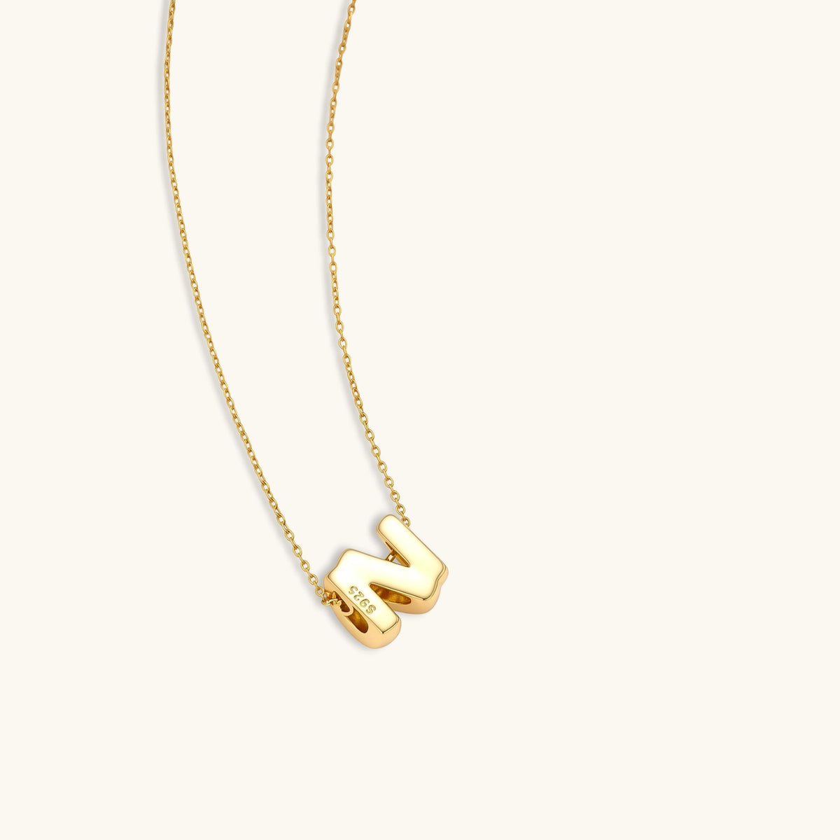 18k gold-plated 925 sterling silver letter n pendant on a delicate adjustable cable chain, cream background.