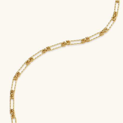 Gold-plated sterling silver chain necklace with alternating love-knot links and elongated oval links, lobster clasp closure.